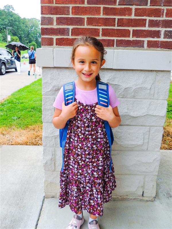 girl student smiling against a brick pillar